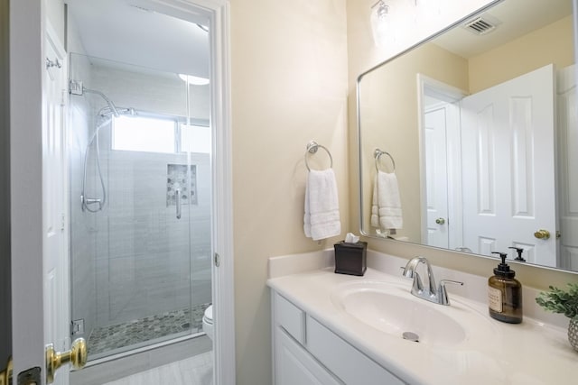 full bathroom with toilet, vanity, a shower stall, and visible vents