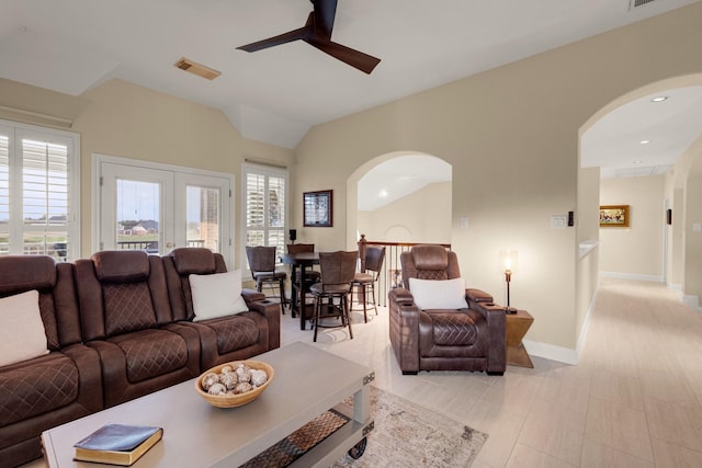 living area featuring baseboards, arched walkways, visible vents, a ceiling fan, and vaulted ceiling