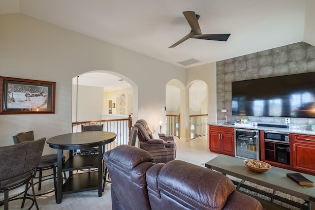 living room with a ceiling fan, wine cooler, visible vents, and vaulted ceiling