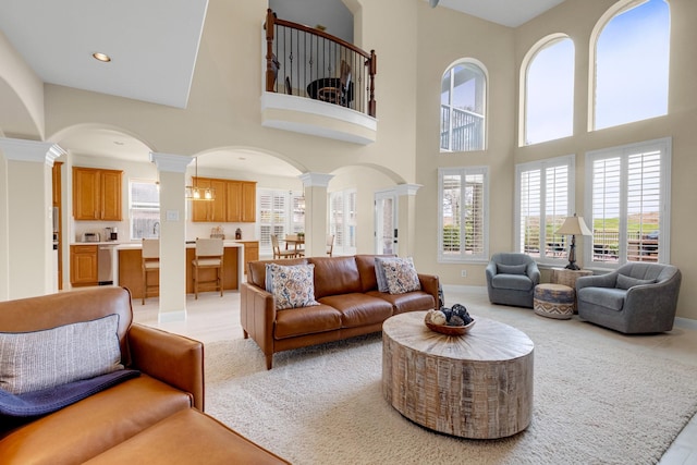 living area with arched walkways, light tile patterned flooring, recessed lighting, baseboards, and ornate columns