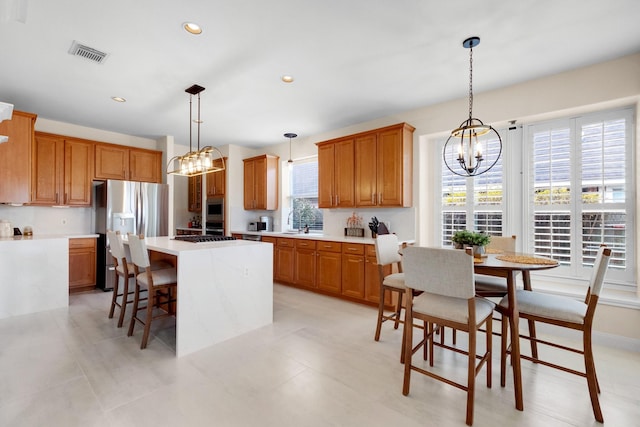 kitchen featuring a notable chandelier, stainless steel appliances, light countertops, visible vents, and a kitchen island