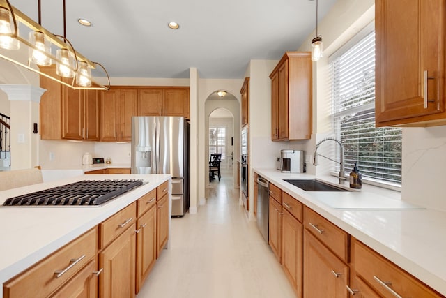 kitchen with arched walkways, stainless steel appliances, a sink, and light countertops