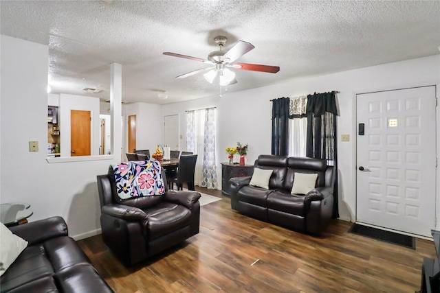 living room with ceiling fan, a textured ceiling, and dark wood-type flooring