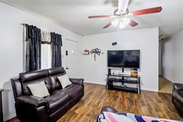 living area with ceiling fan, a textured ceiling, and wood finished floors