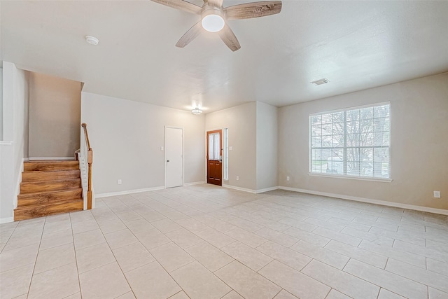 empty room featuring ceiling fan, stairway, visible vents, and baseboards