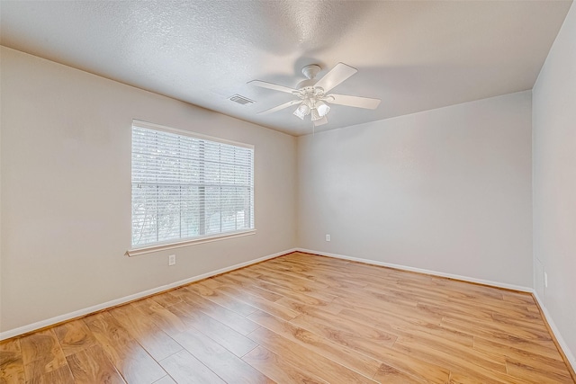 empty room with light wood finished floors, ceiling fan, visible vents, and baseboards