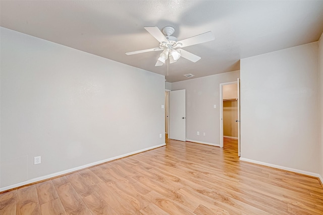 spare room with baseboards, ceiling fan, visible vents, and light wood-style floors