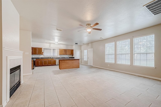 kitchen with visible vents, brown cabinetry, open floor plan, a healthy amount of sunlight, and ceiling fan