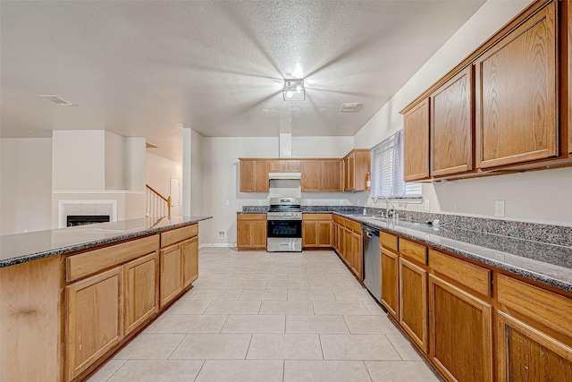 kitchen with appliances with stainless steel finishes, dark stone countertops, a sink, and visible vents