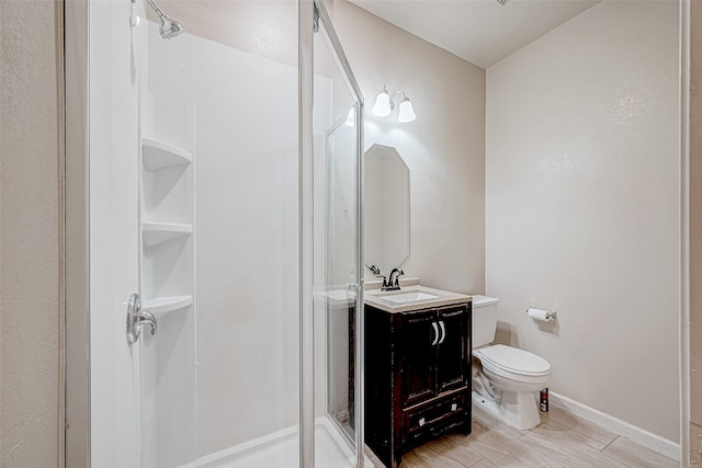 full bath featuring a stall shower, vanity, toilet, and baseboards