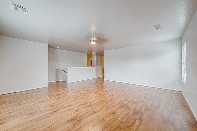 unfurnished room with light wood-style flooring, visible vents, and baseboards