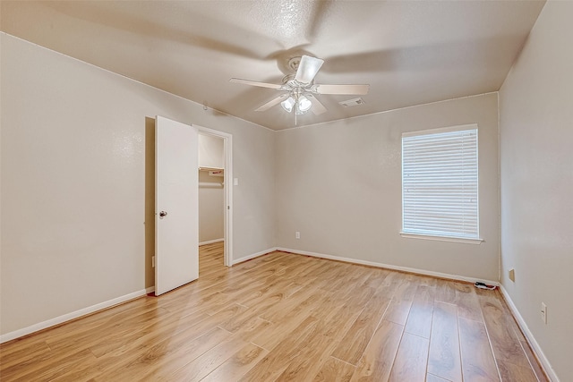 empty room with visible vents, baseboards, light wood-style flooring, and a ceiling fan