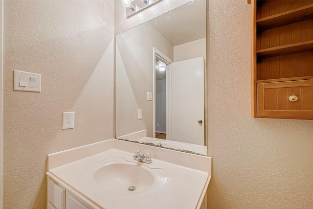 bathroom featuring a textured wall and vanity