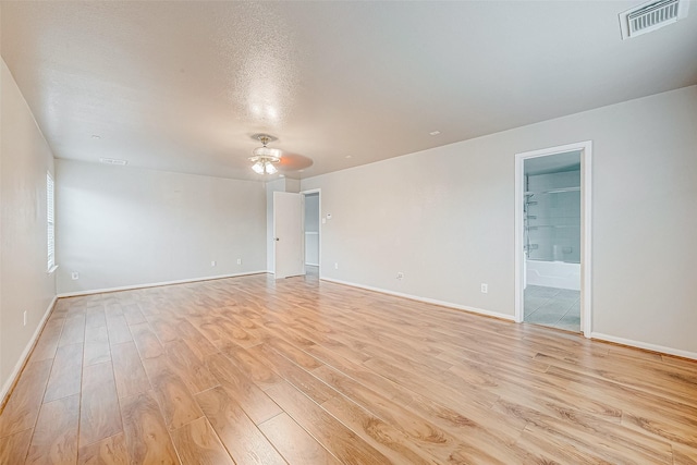 spare room featuring baseboards, a ceiling fan, visible vents, and light wood-style floors