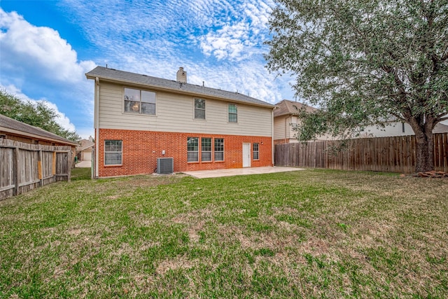 rear view of property featuring brick siding, a patio, a chimney, a lawn, and a fenced backyard