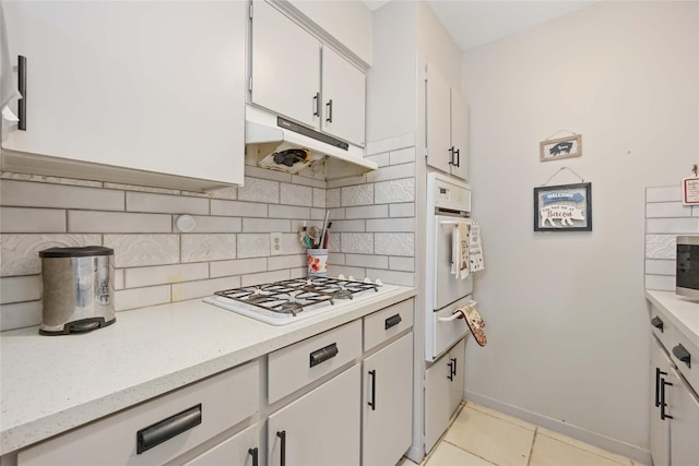 kitchen featuring white appliances, tasteful backsplash, white cabinets, light countertops, and under cabinet range hood