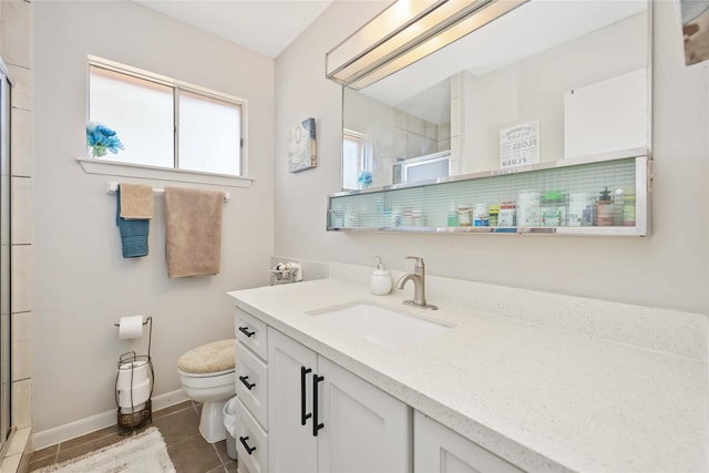 bathroom with a stall shower, baseboards, vanity, and toilet