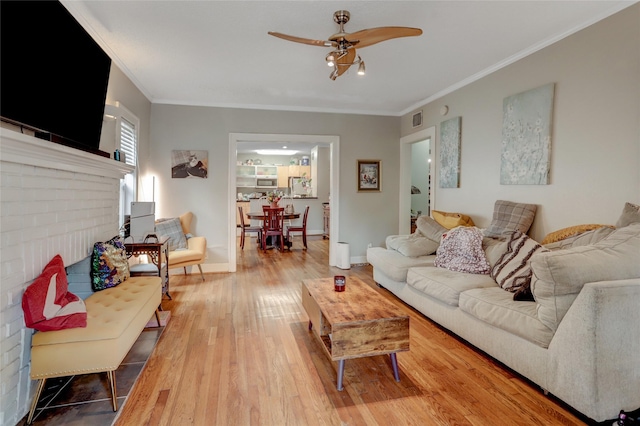 living room with baseboards, visible vents, ornamental molding, and wood finished floors