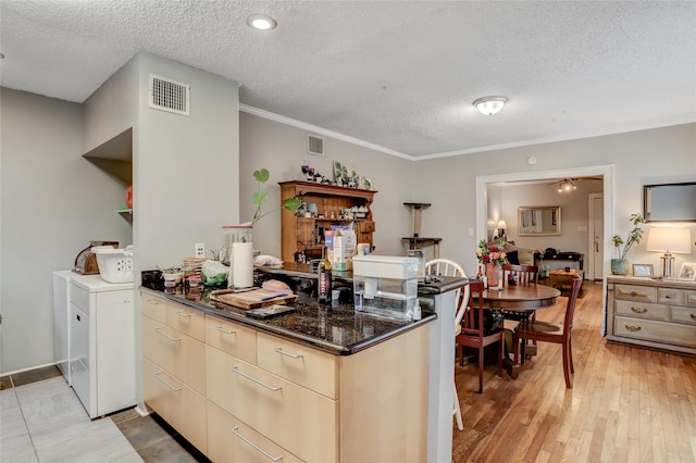 kitchen featuring a textured ceiling, a peninsula, light wood finished floors, and visible vents