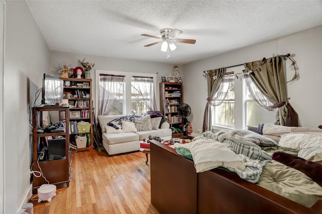 bedroom featuring light wood-style floors, a ceiling fan, and a textured ceiling