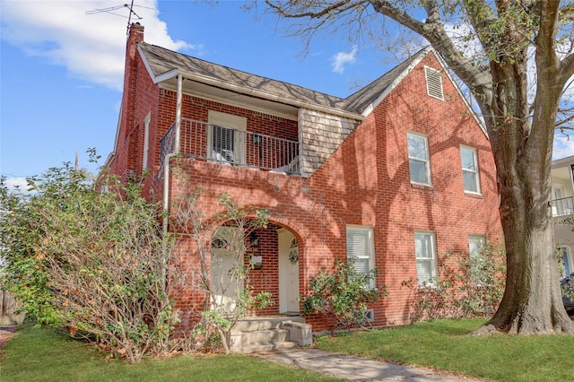 view of front of home featuring brick siding, a chimney, and a front lawn