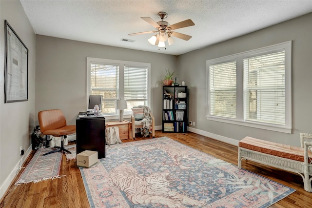 office with a healthy amount of sunlight, a textured ceiling, visible vents, and wood finished floors