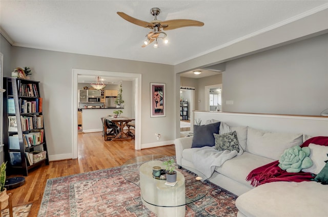 living room featuring baseboards, a ceiling fan, ornamental molding, a textured ceiling, and light wood-style floors