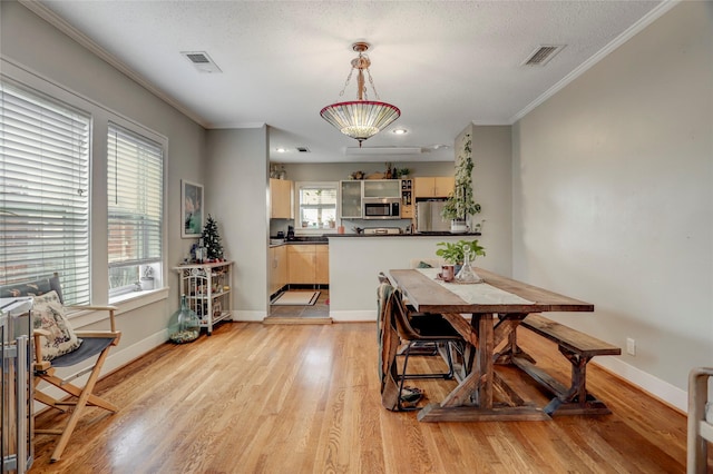 dining area with baseboards, ornamental molding, visible vents, and light wood-style floors