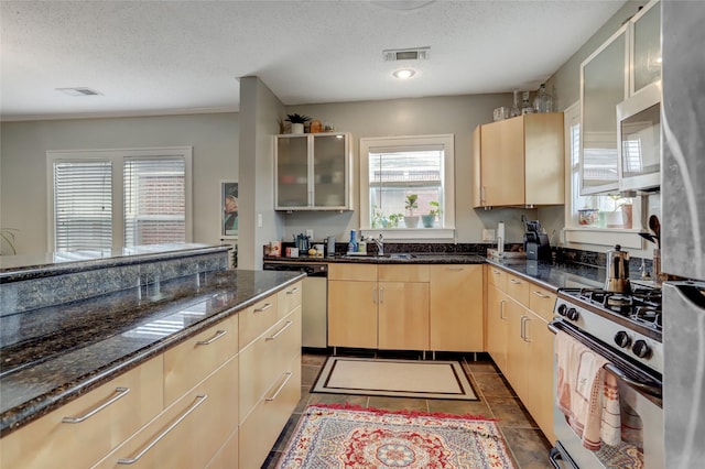 kitchen featuring visible vents, appliances with stainless steel finishes, light brown cabinets, and glass insert cabinets