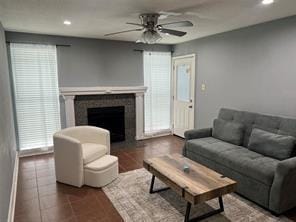 living room featuring ceiling fan, dark tile patterned flooring, a tiled fireplace, and recessed lighting