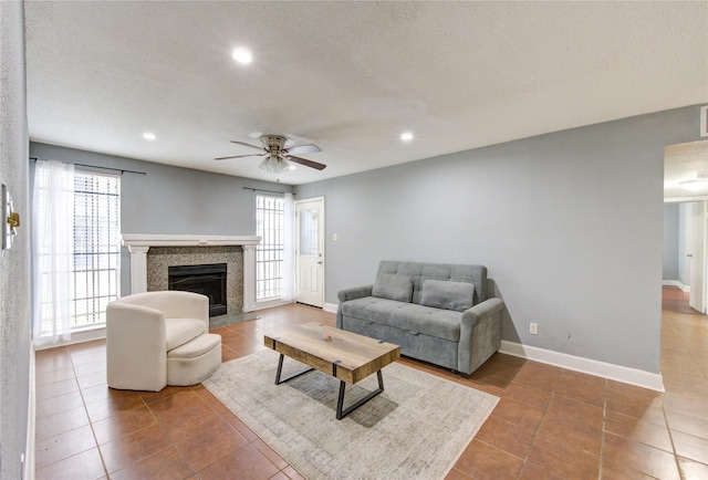 tiled living area with ceiling fan, a textured ceiling, recessed lighting, a fireplace, and baseboards