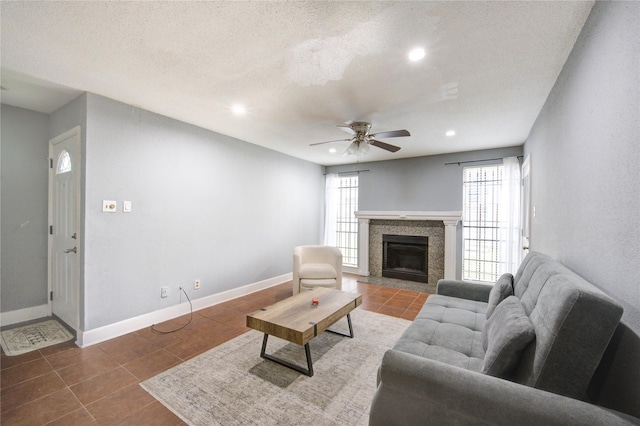 living area featuring a tiled fireplace, tile patterned flooring, plenty of natural light, and baseboards