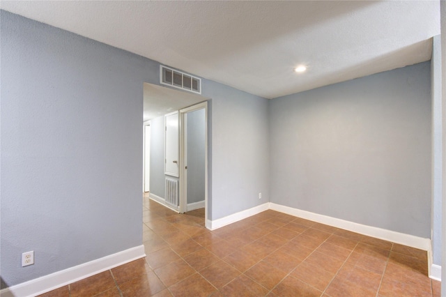 tiled empty room with visible vents and baseboards