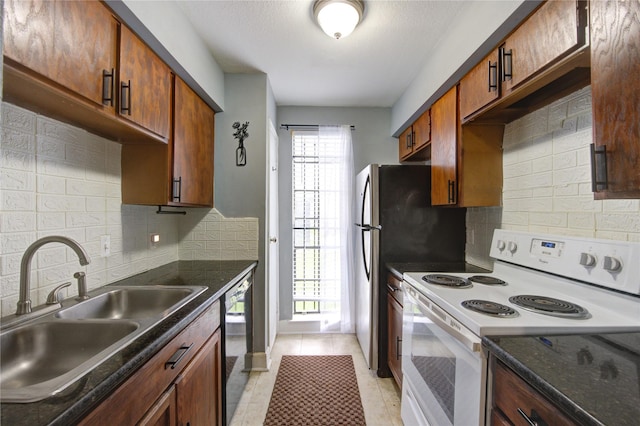 kitchen with light tile patterned floors, tasteful backsplash, dark countertops, white electric range, and a sink