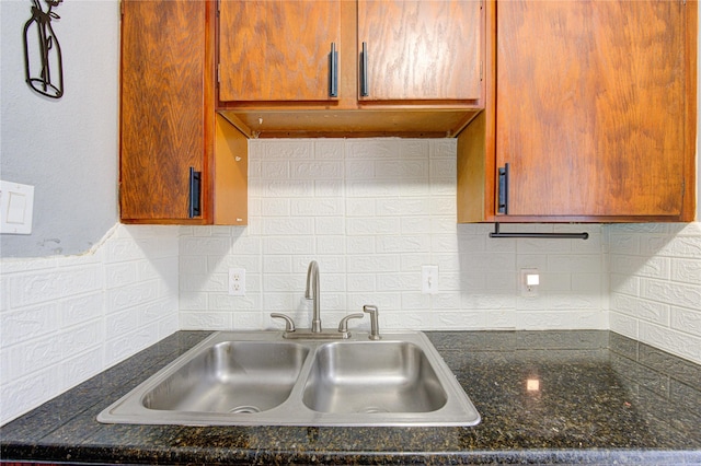 kitchen featuring brown cabinetry, a sink, and backsplash