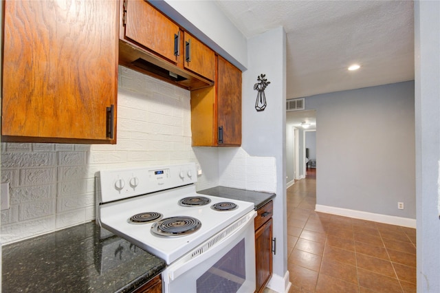 kitchen with baseboards, visible vents, electric stove, dark tile patterned flooring, and backsplash