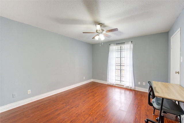 unfurnished office with a ceiling fan, a textured ceiling, baseboards, and dark wood-type flooring