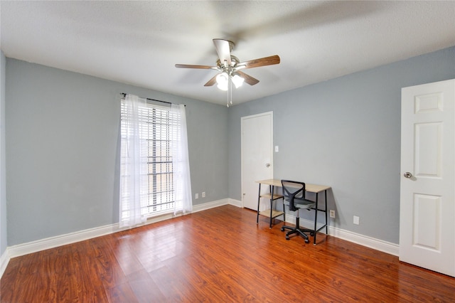 empty room featuring wood finished floors, a ceiling fan, and baseboards