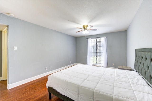 bedroom with ceiling fan, a textured ceiling, baseboards, and wood finished floors