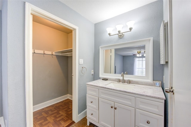 bathroom featuring a walk in closet, vanity, and baseboards