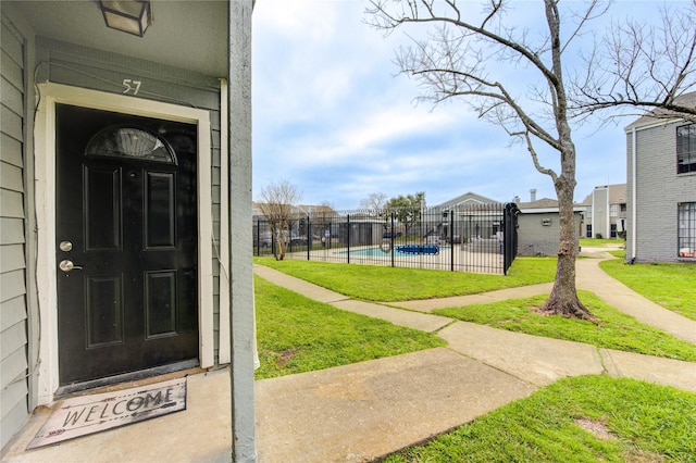 entrance to property featuring fence, a fenced in pool, and a yard