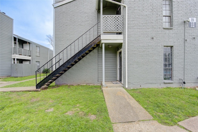 view of exterior entry featuring a lawn and brick siding