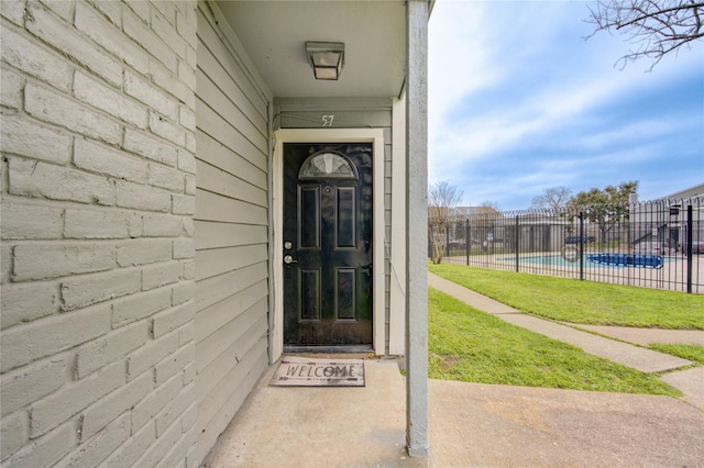 view of exterior entry with fence and a fenced in pool