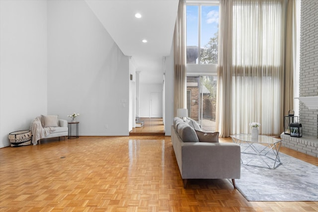 living room featuring a high ceiling, baseboards, a fireplace, and recessed lighting