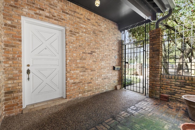 property entrance featuring a gate and brick siding