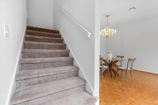 stairway with baseboards, visible vents, and an inviting chandelier