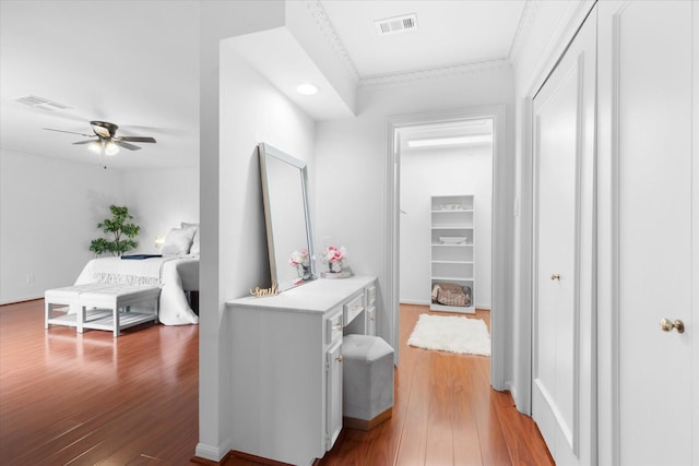 hall featuring wood finished floors, visible vents, and crown molding