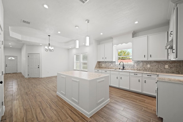 kitchen featuring a center island, pendant lighting, light countertops, and white cabinets