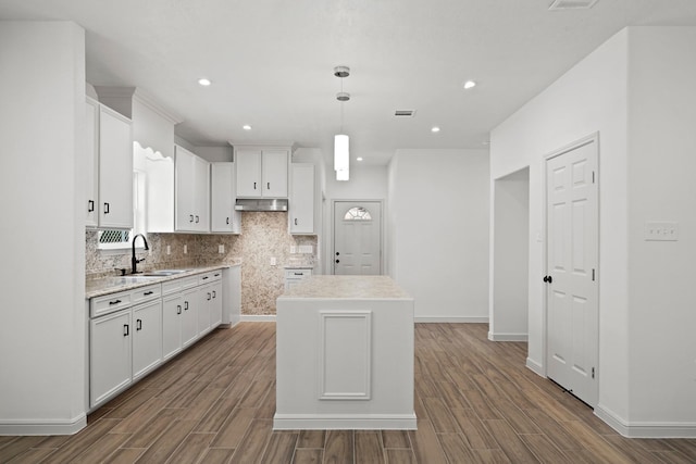 kitchen featuring light countertops, hanging light fixtures, a sink, and a center island