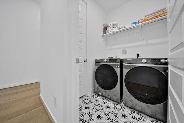 clothes washing area with laundry area, washer and clothes dryer, baseboards, and wood finished floors